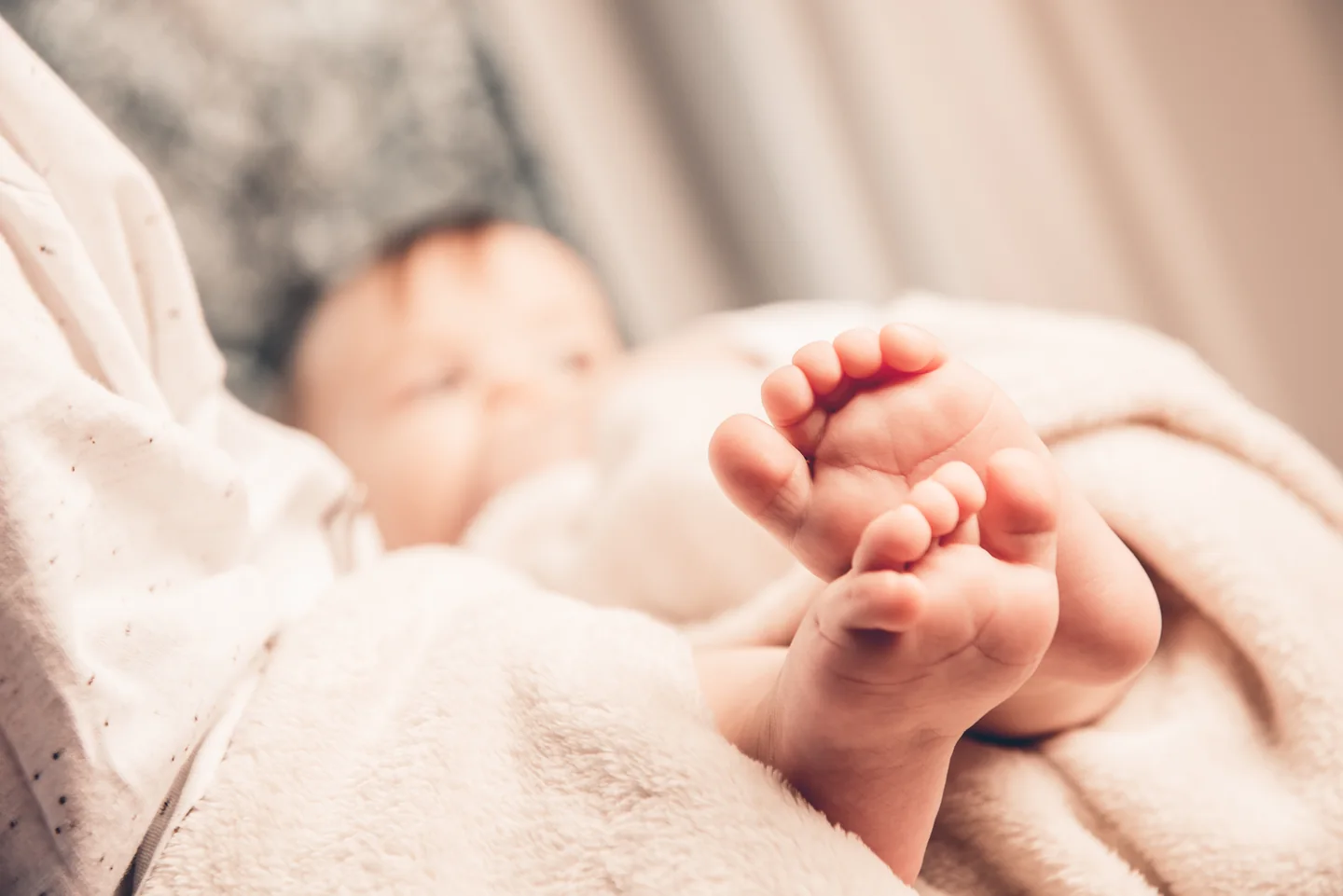 Die kleinen Füße eines schlafenden Babys liegen geborgen in den Händen eines Erwachsenen