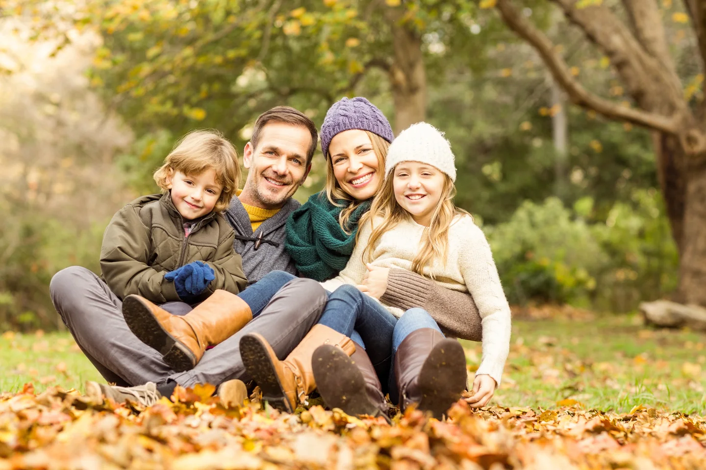 Eine Familie mit zwei Kindern sitzt lachend im Herbstlaub