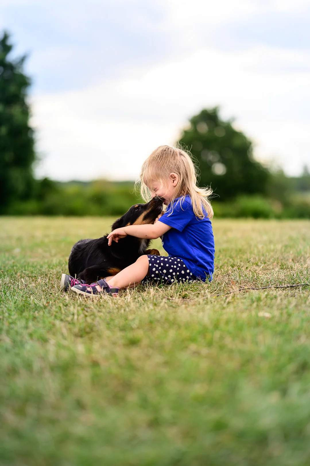 Eine Frau sitzt mit ihrem Hund vertraut auf einer Wiese